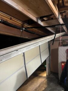 A damaged garage door off its tracks, requiring repair from AAA Garage Door Services in Renton, WA