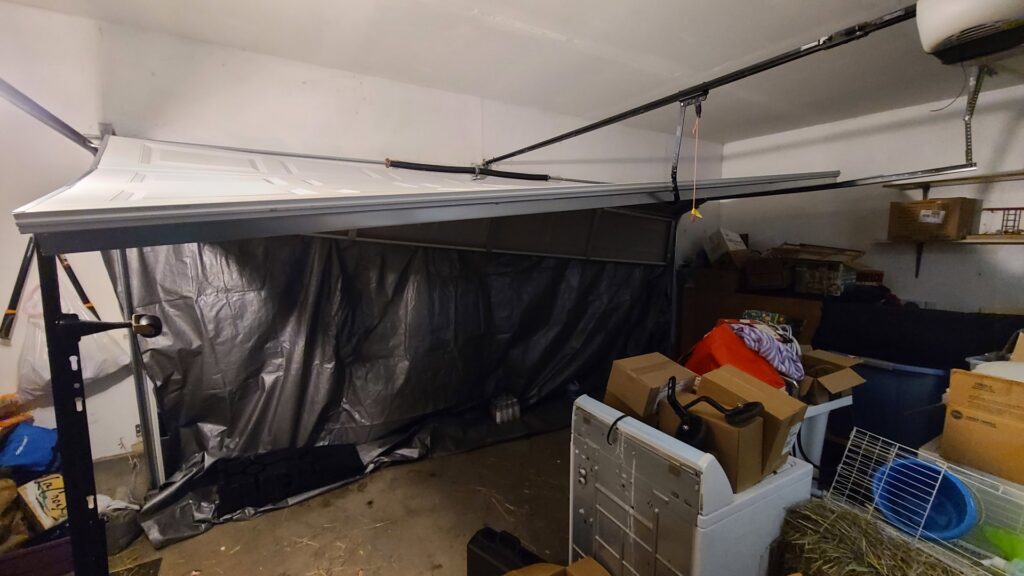 A damaged garage door undergoing repair or replacement by Revolution Garage Door, LLC in Corvallis, OR.