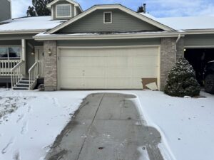 A damaged garage door in the snow, indicating a need for repair or replacement by Strongdoor garage in Denver, CO.
