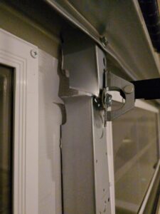 Close-up of a damaged garage door track and panel requiring repair by American Overhead Door in Madison, AL