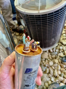 A technician holding a damaged HVAC capacitor during a repair service at Heart City Heating & Cooling in Elkhart, IN.