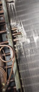 Close-up of damaged HVAC coil fins, indicating a repair or cleaning service by By the Bay Mechanical in Prince Frederick, MD