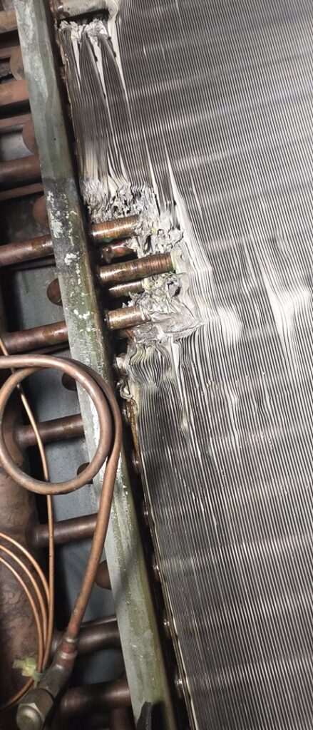 Close-up of damaged HVAC coil fins, indicating a repair or cleaning service by By the Bay Mechanical in Prince Frederick, MD