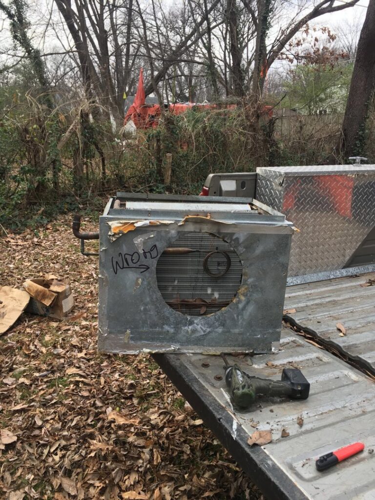 A damaged HVAC coil unit on the back of a truck, indicating removal or replacement by West Tennessee Heat & Air in Memphis, TN