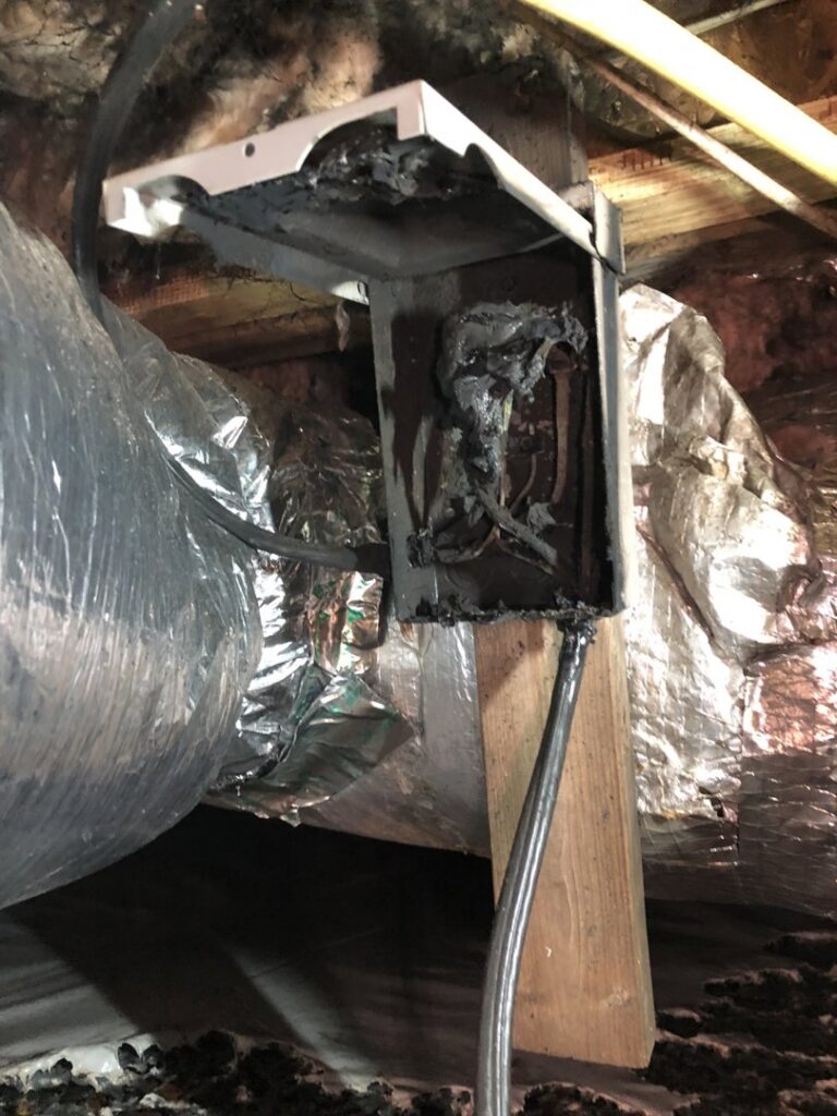 A damaged electrical box and HVAC ductwork in a crawl space, indicating a repair job by Workman Mechanical in Graham, NC.