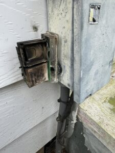 A damaged outdoor HVAC electrical disconnect box being inspected by Tadlock Heating & Air Conditioning in Tallahassee, FL