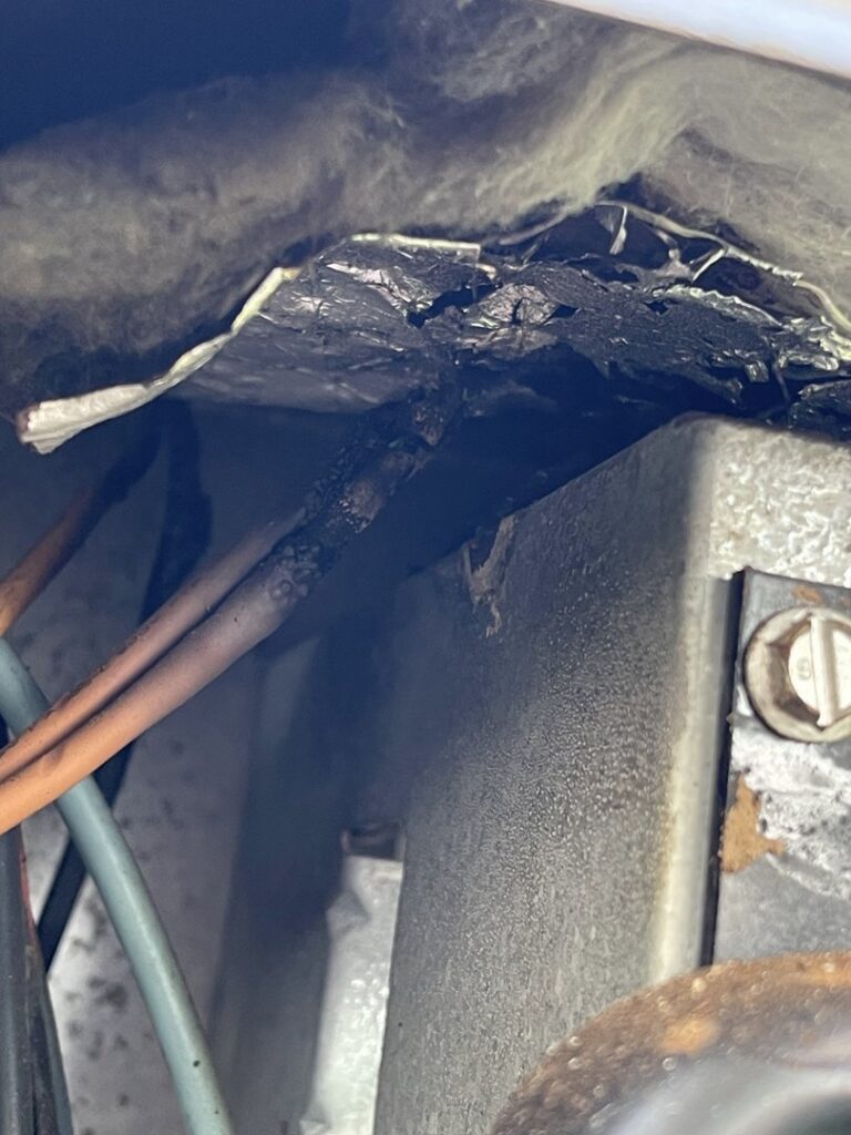 Close-up of burnt or damaged electrical wiring and insulation inside an HVAC unit, requiring expert repair from DeltaCool in Jonesboro, AR.