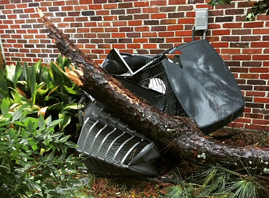 Damaged outdoor HVAC unit crushed by a fallen tree, showing a general junk removal job by RHC Heating and Cooling in Albany, GA.