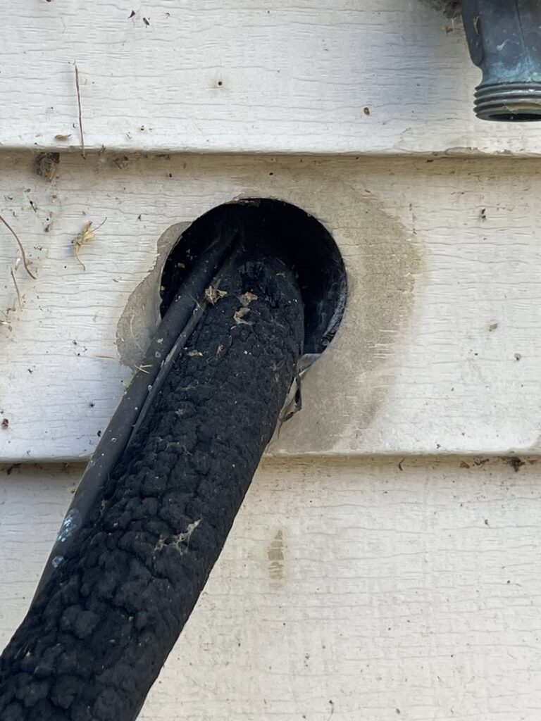 A damaged insulated pipe entering a house, a potential wildlife entry point, addressed by Ramer Pest Control in Fort Wayne, IN.