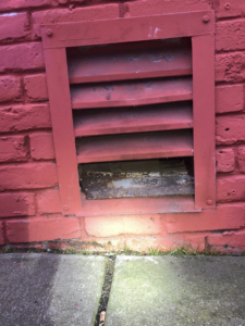 A damaged vent on a red brick wall, indicating a potential pest entry point, inspected by Sophie's Pest Solutions in Oakland, CA.