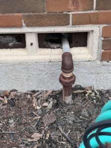 A damaged vent pipe in a brick wall, a potential entry point for wildlife or pests, inspected by BBK Pest Control in Dallas, TX.