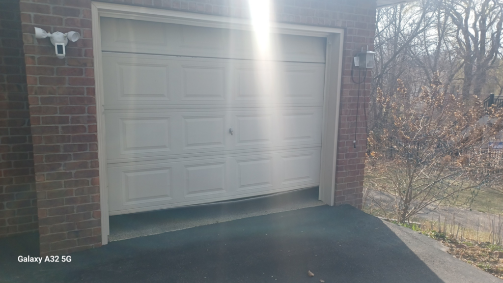 A damaged white panel garage door requiring repair, showcasing a typical job for Garage Door Technologies in Minneapolis, MN