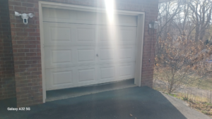 A damaged white panel garage door requiring repair, showcasing a typical job for Garage Door Technologies in Minneapolis, MN