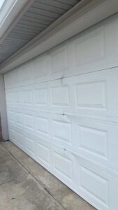 A damaged white garage door showing dents, ready for repair by Legacy Garage Doors & Repairs in Church Point, LA.