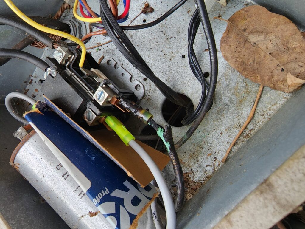 Damaged wiring and components inside an outdoor AC unit, indicating a repair job by Sizemore Heating & Air, LLC in Chapel Hill, NC