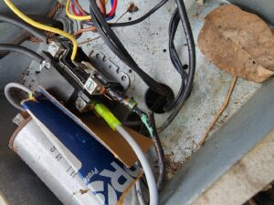 Damaged wiring and components inside an outdoor AC unit, indicating a repair job by Sizemore Heating & Air, LLC in Chapel Hill, NC