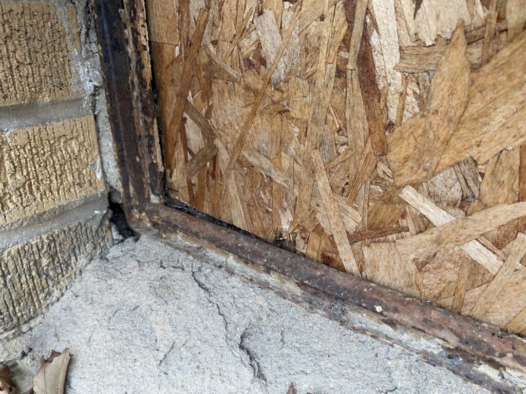 Damaged wooden siding and brick wall showing a potential pest entry point or structural issue, inspected by Moderno Pest Control in Fort Wayne, IN.