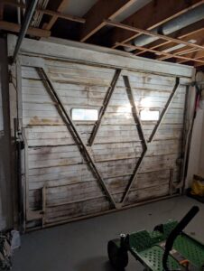 An old, damaged wooden garage door in need of repair or replacement by Gilliam Services LLC in Johnson City, TN.