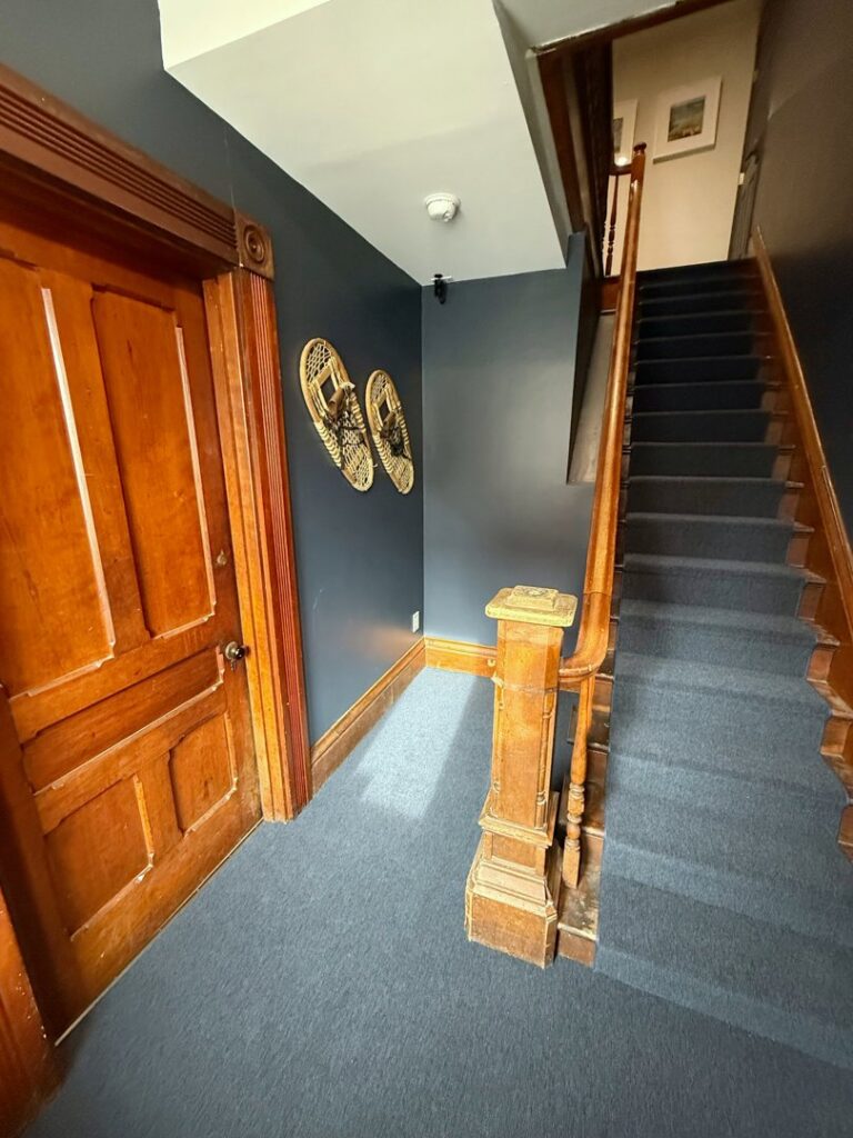 A dark blue carpeted staircase and hallway installed by Concord Carpet Center LLC in Concord, NH