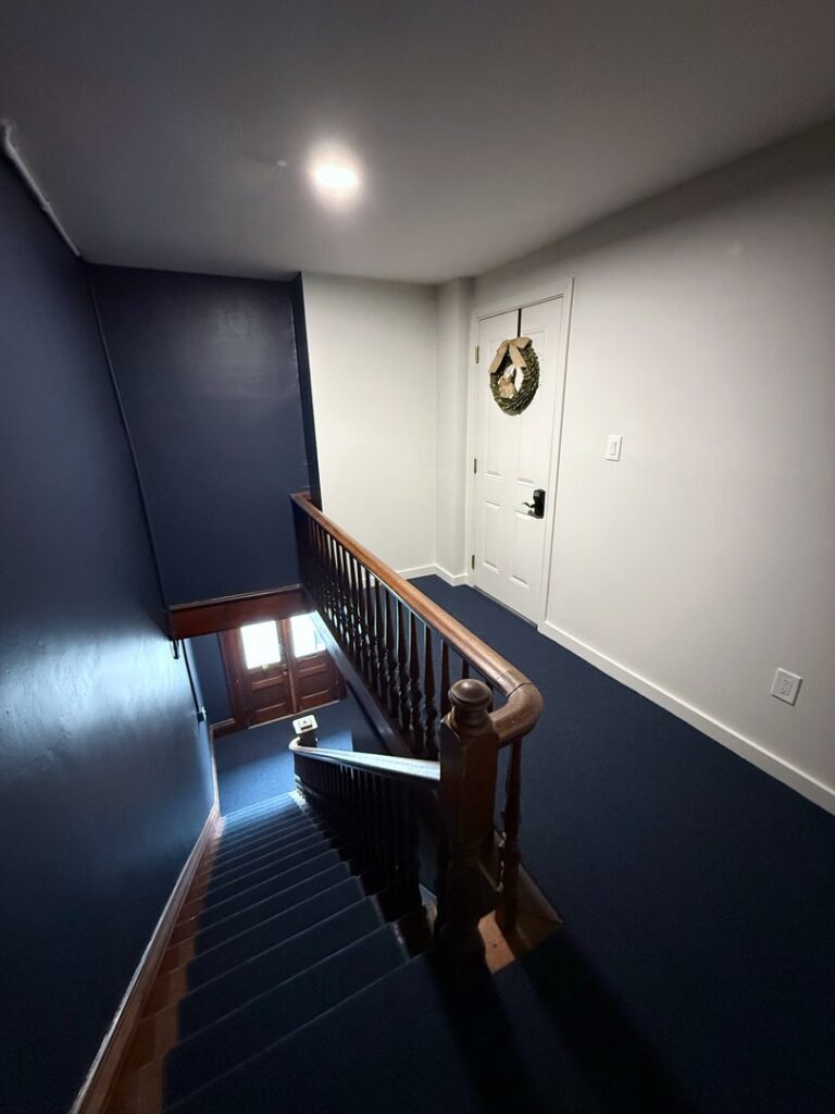 A dark blue carpeted stairwell installed by Concord Carpet Center LLC in Concord, NH