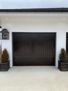 A beautiful dark brown carriage-style garage door installed on a white home by Signature Garage Doors in Huntsville, AL.