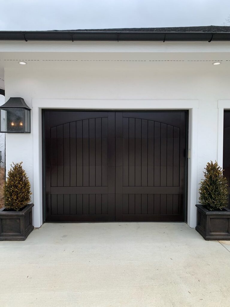 A beautiful dark brown carriage-style garage door installed on a white home by Signature Garage Doors in Huntsville, AL.