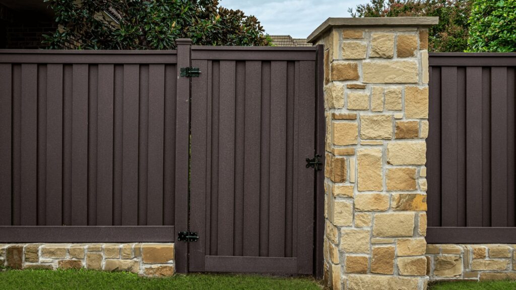 A dark brown privacy fence gate with stone pillars, expertly installed by Superior Fence & Rail of Arkansas in Springdale, AR.