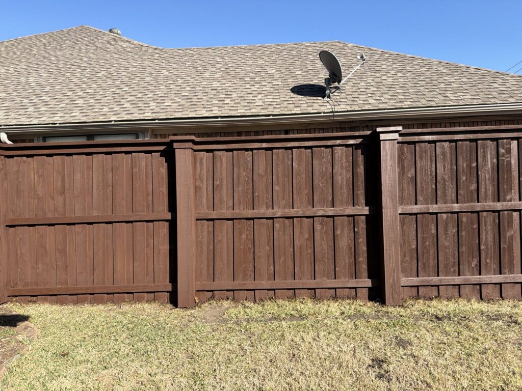 A dark brown stained wood fence in a residential backyard by Fence Defense in Plano, TX
