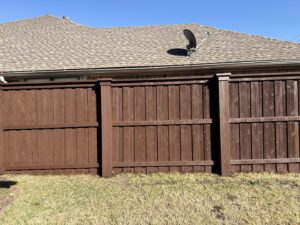 A dark brown stained wood fence in a residential backyard by Fence Defense in Plano, TX