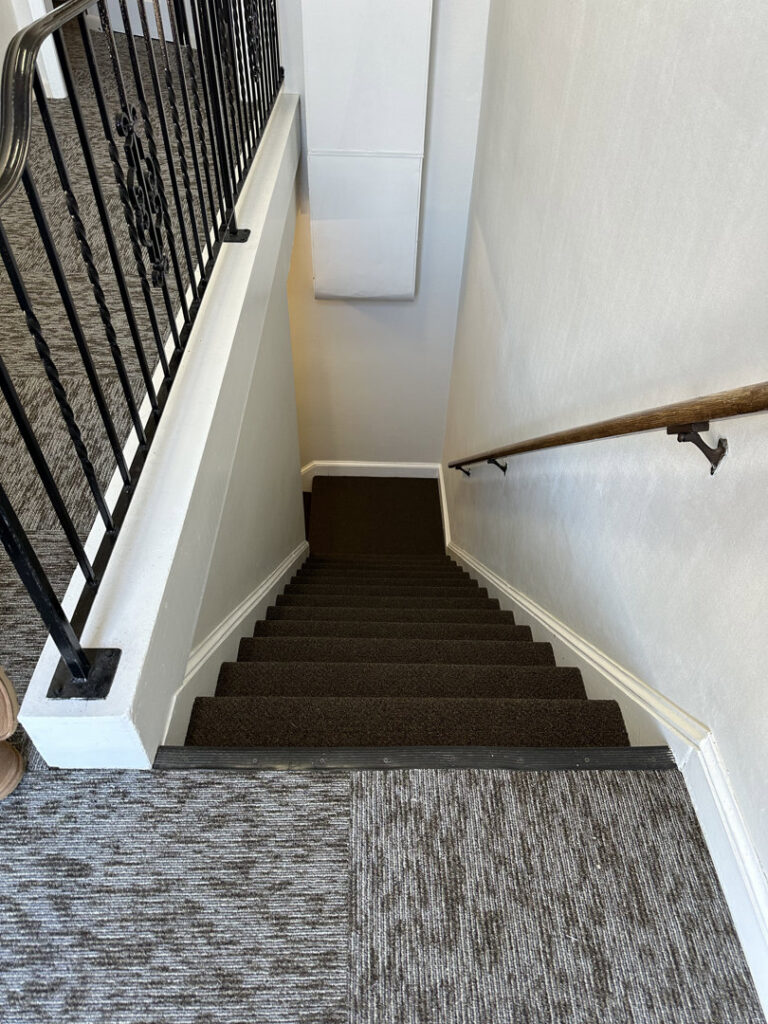 A dark brown wall-to-wall carpet expertly installed on a residential staircase by RugSale by Kaoud Rugs in West Hartford, CT.