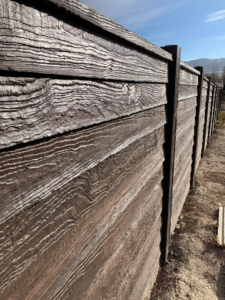 A newly installed dark concrete fence with a wood grain texture by BroKrete Fencing LLC in Salt Lake City, UT