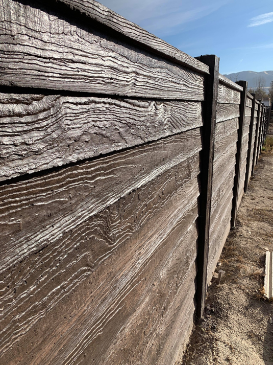 A newly installed dark concrete fence with a wood grain texture by BroKrete Fencing LLC in Salt Lake City, UT