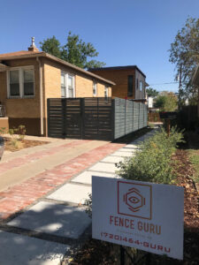 A stylish dark gray horizontal slat fence with a matching gate, installed along a driveway by Fence Guru LLC in Denver, CO.