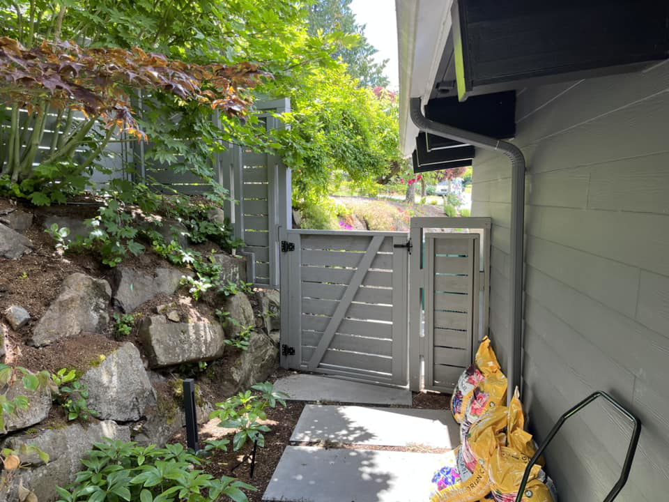 A dark gray horizontal slat fence and gate providing access to a side yard by Webb Fencing Pros in Seattle, WA.