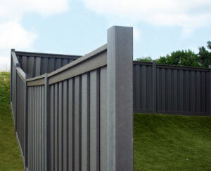 A dark gray privacy fence installed on a sloped lawn by American Fence Company - Omaha in Omaha, NE.