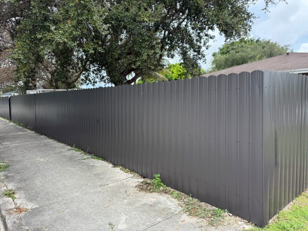 A long dark gray scalloped metal perimeter fence installed by Osuna Ornamental Fences & Gates in Cutler Bay, FL.