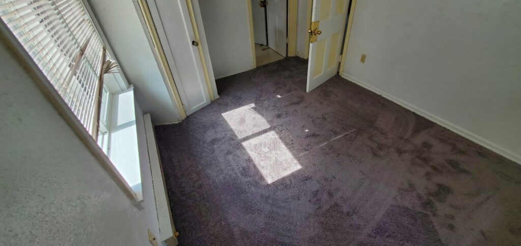 A bedroom with a dark grey carpet installation completed by Carpet Liquidators in Linthicum Heights, MD.