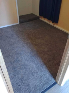 A newly installed dark grey carpet in a room with a raised section by Carpet Direct of Northern Colorado in Loveland, CO.