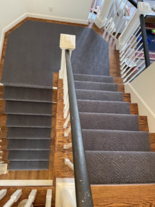 A dark grey carpet runner installed on a split staircase and landing by Jimmy's Flooring in Louisville, KY