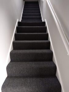 Newly installed dark grey carpet on stairs by New City Carpet And Flooring, a professional carpet contractor in Chicago, IL