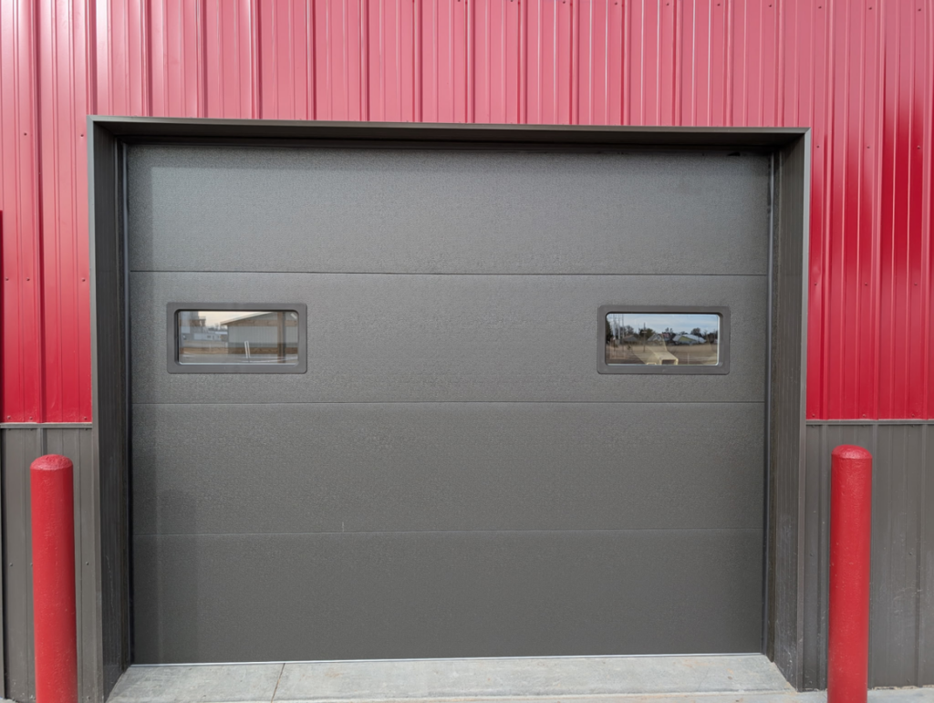 A dark grey commercial garage door with windows installed by Usa Garage Door Services and Construction, LLC at 1206 E 6th St, USA.