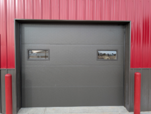 A dark grey commercial garage door with windows installed by Usa Garage Door Services and Construction, LLC at 1206 E 6th St, USA.