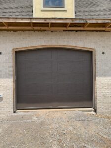 A dark grey garage door installed on a new construction home by Signature Garage Doors in Huntsville, AL.