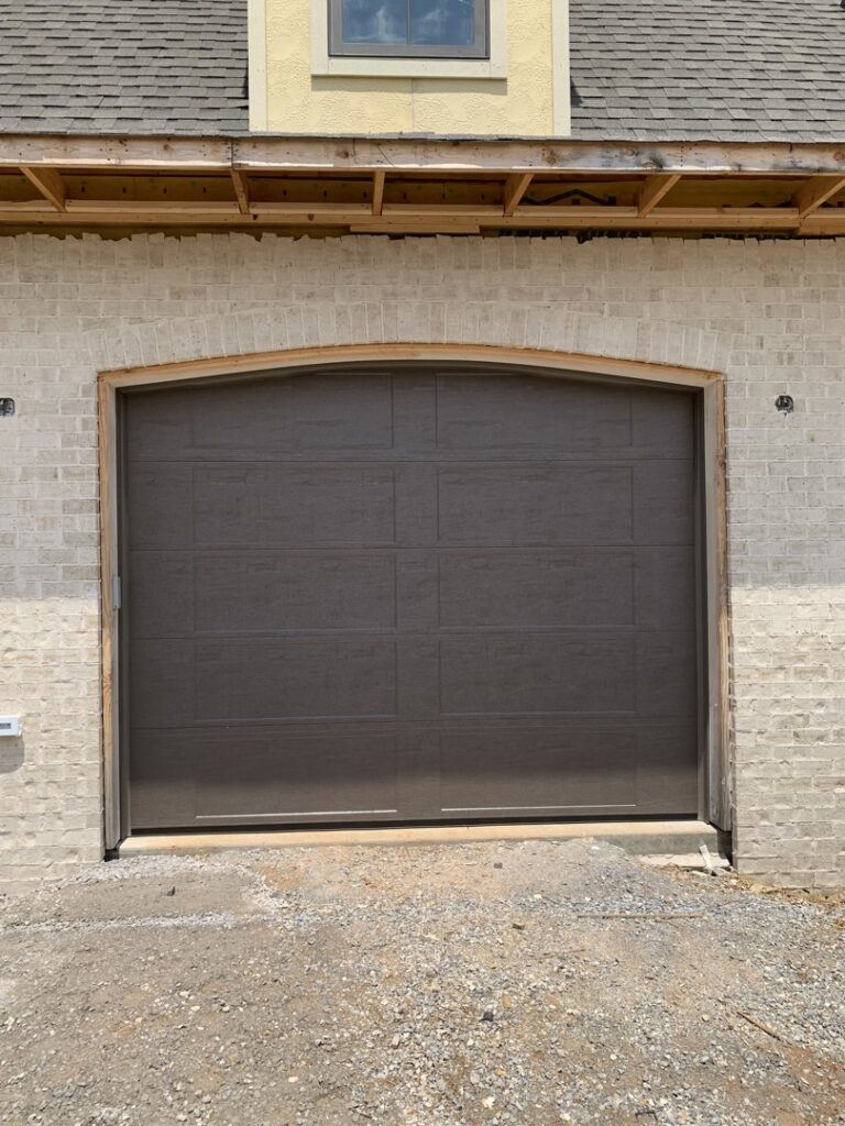 A dark grey garage door installed on a new construction home by Signature Garage Doors in Huntsville, AL.