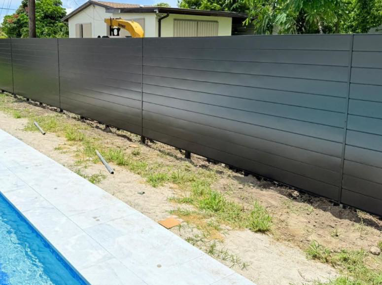 A long dark grey horizontal slat fence installed alongside a swimming pool by HD Multi Service USA INC in Miami, FL.