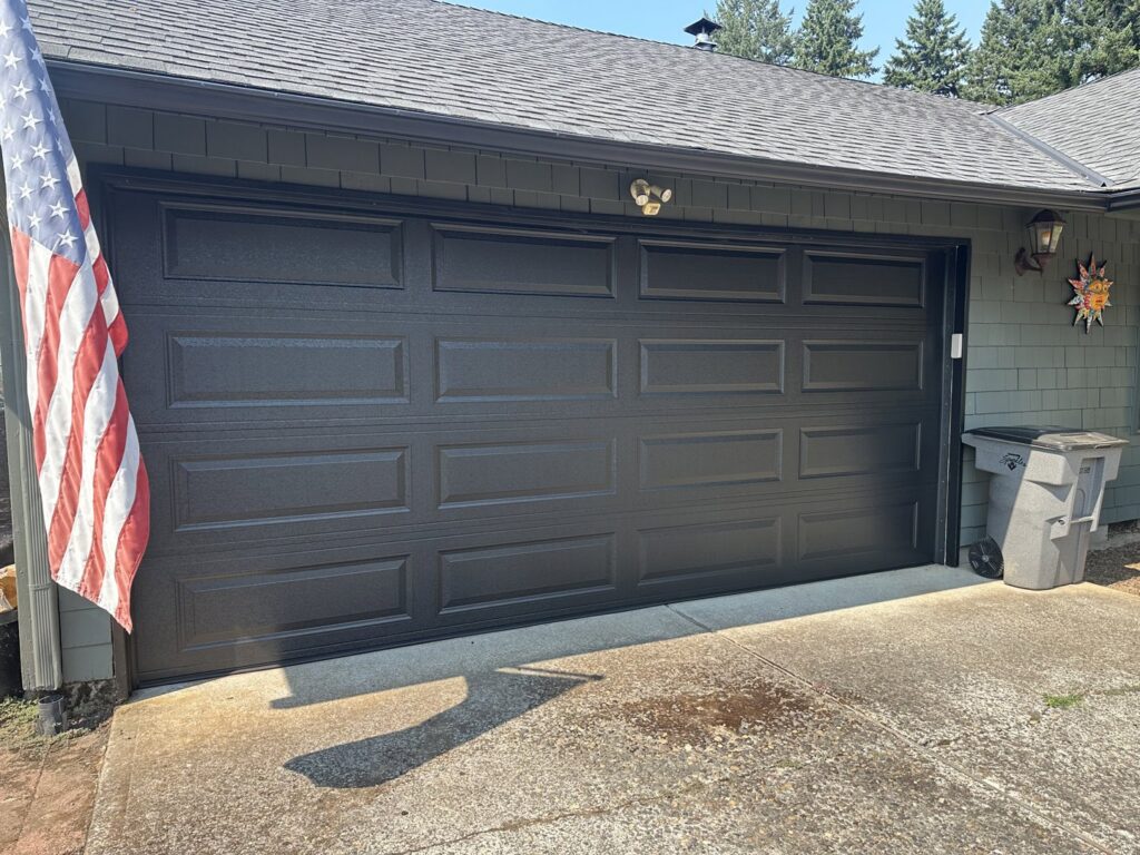 A dark paneled garage door on a residential home, installed by Coast To Coast Garage Door LLC in Vancouver, WA.