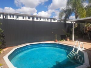 A dark privacy fence enclosing a backyard pool area, installed by Allende J. Service Corp in Miami, FL.