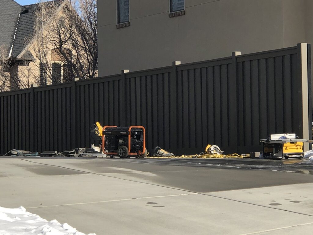 A dark privacy fence with construction tools and equipment in front, indicating a recent job by All Over Fence Idaho in Jerome, ID