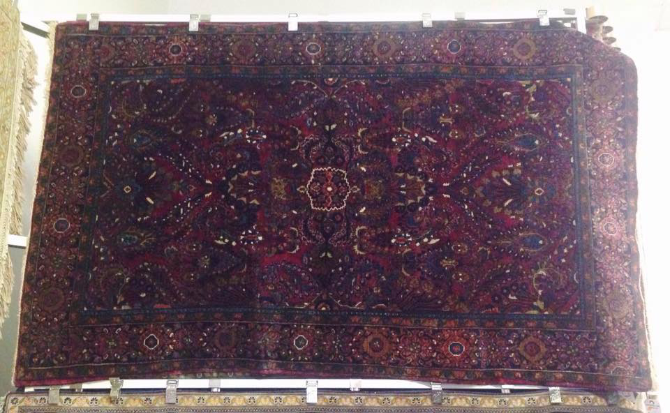 A dark red oriental rug with intricate patterns displayed by Iowa Oriental Rug Co in Davenport, IA.