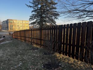 A dark stained wooden picket fence running alongside a street by Brothers Fence Co. in Madison, WI.